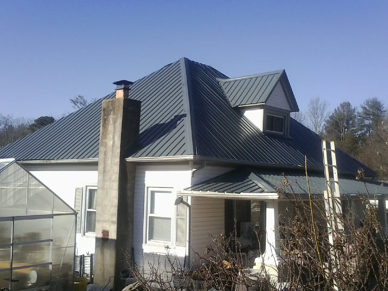 Dark blue standing seam metal roof on a white farmhouse with dormer — Slate & Tile Roof Repair by Roofing Brothers in Lagrange