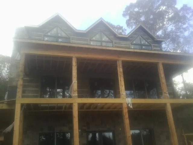 Dormers and porch framing on a large log home under construction — Roof Coating work by our crew in Lagrange